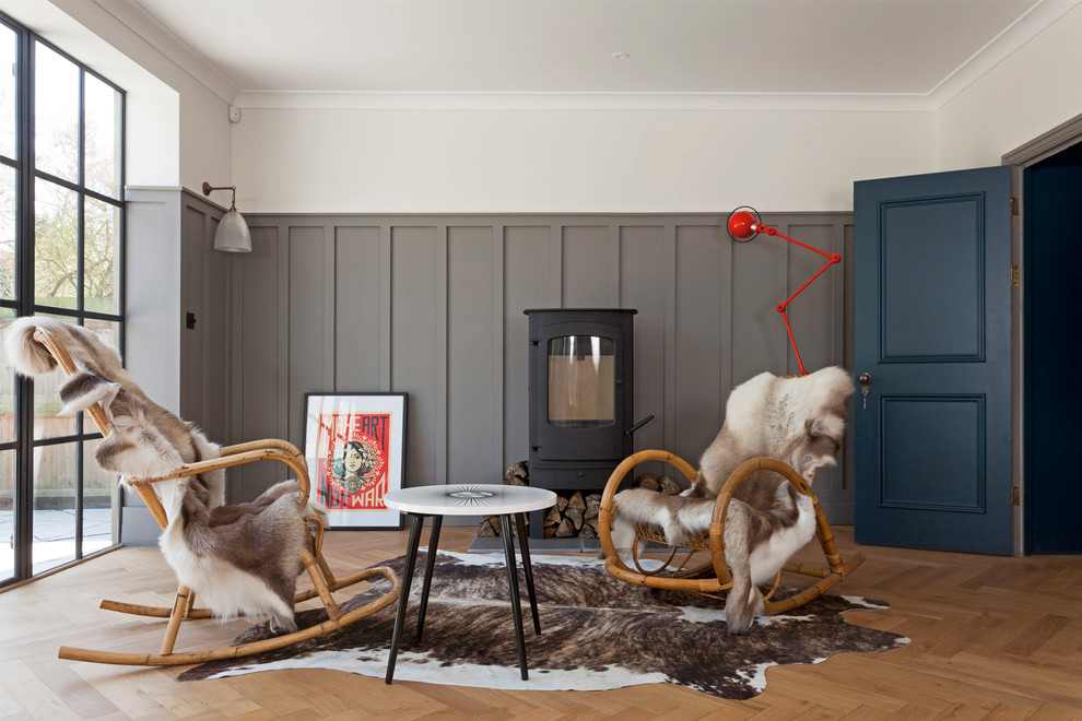 Modelo de salón escandinavo sin televisor con paredes beige, suelo de madera en tonos medios y estufa de leña
