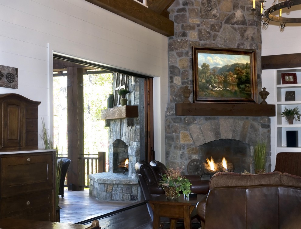 Imagen de salón para visitas abierto rústico de tamaño medio sin televisor con paredes blancas, suelo de madera oscura, chimenea de doble cara y marco de chimenea de piedra