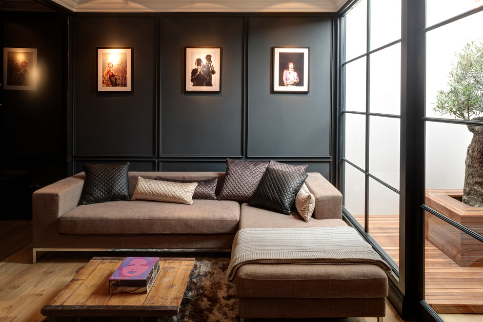 Contemporary living room in London with black walls and light hardwood flooring.