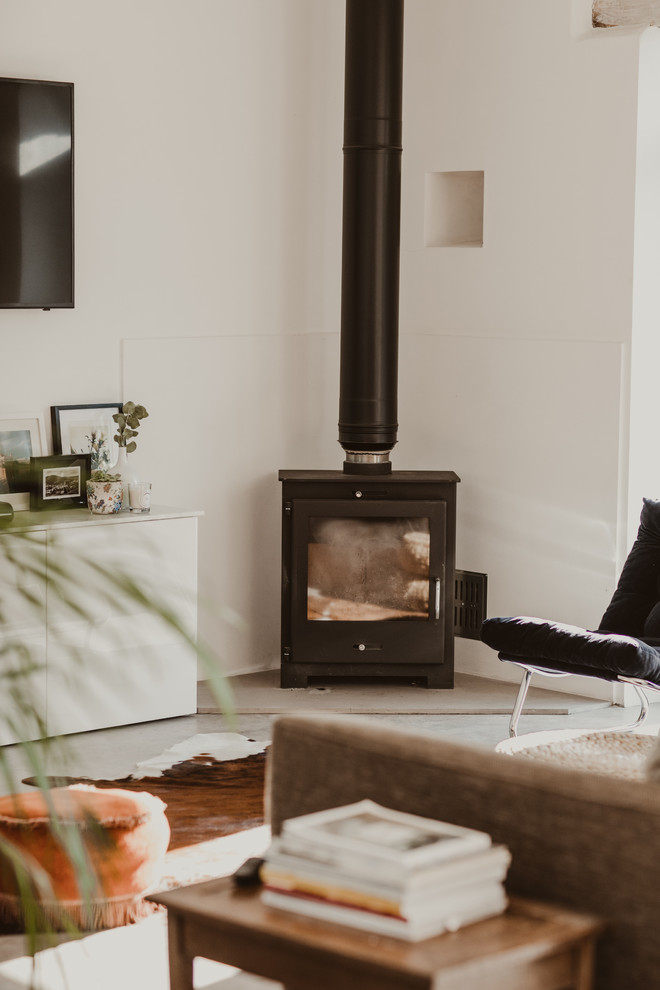 This is an example of a medium sized scandi open plan living room in Other with grey walls, concrete flooring, a wood burning stove, a wall mounted tv and grey floors.
