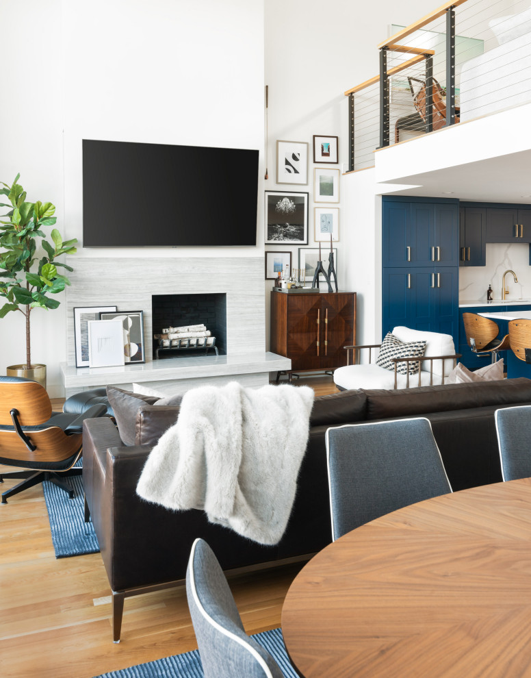 На фото: открытая гостиная комната среднего размера в стиле неоклассика (современная классика) с серыми стенами, светлым паркетным полом, стандартным камином, фасадом камина из камня, телевизором на стене и коричневым полом