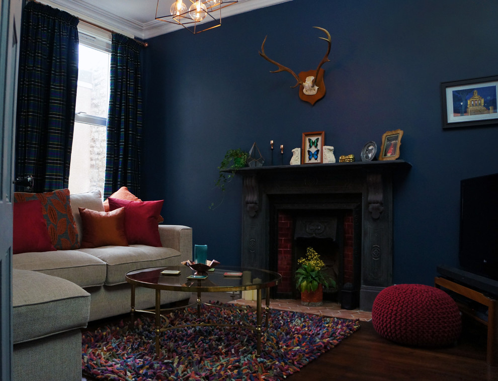 Inspiration för ett mellanstort eklektiskt separat vardagsrum, med blå väggar, mörkt trägolv, en standard öppen spis, en spiselkrans i sten och TV i ett hörn