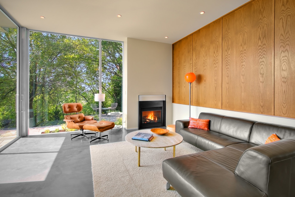 シアトルにある広いコンテンポラリースタイルのおしゃれな独立型リビング (コンクリートの床、白い壁、標準型暖炉、テレビなし、漆喰の暖炉まわり、グレーの床) の写真