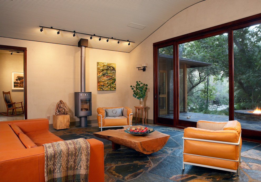 Photo of a contemporary living room in Los Angeles with beige walls, slate flooring and a wood burning stove.