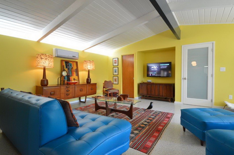 Modelo de salón abierto vintage sin chimenea con paredes amarillas y televisor colgado en la pared