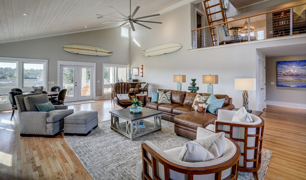 Large beach style open plan living room in Other with grey walls, light hardwood flooring and feature lighting.