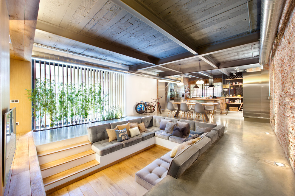 Großes, Repräsentatives, Offenes Industrial Wohnzimmer ohne Kamin mit bunten Wänden, braunem Holzboden und TV-Wand in Madrid