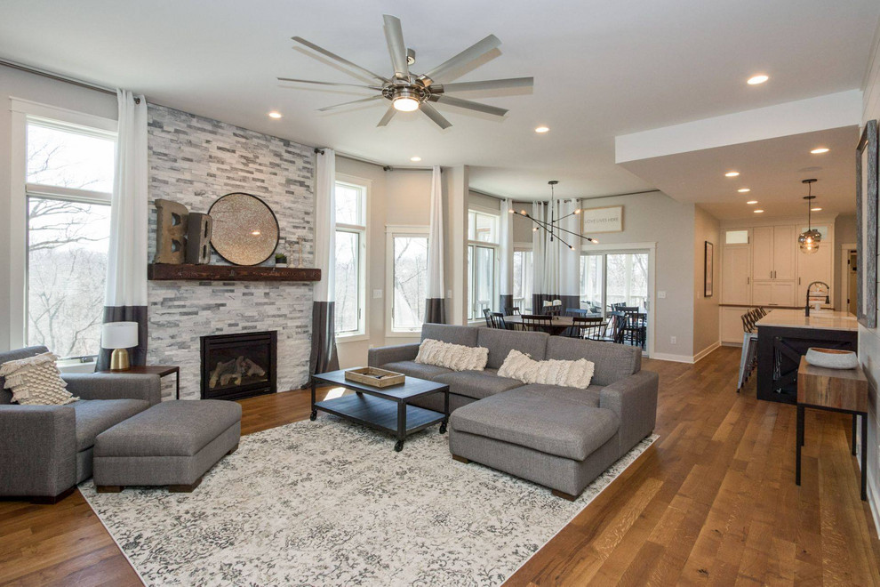 Photo of a medium sized contemporary formal open plan living room in Cedar Rapids with white walls, medium hardwood flooring, a standard fireplace, a stone fireplace surround, a built-in media unit and brown floors.