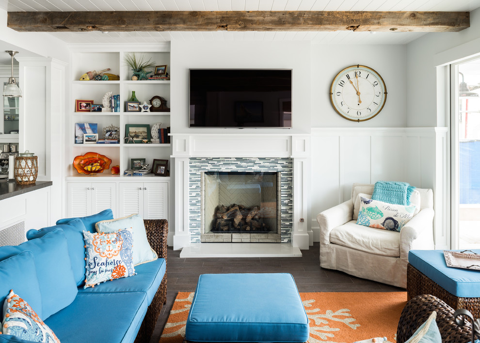 Стильный дизайн: гостиная комната в морском стиле с белыми стенами, стандартным камином, фасадом камина из плитки и синим диваном - последний тренд