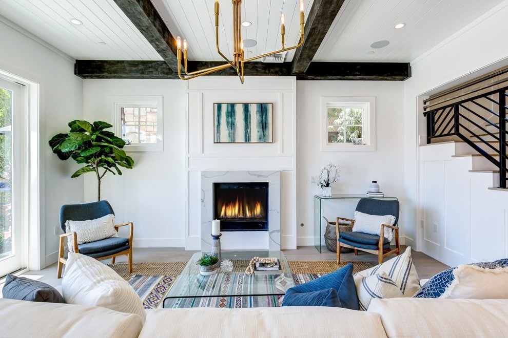 Photo of a coastal formal living room in Los Angeles with white walls, light hardwood flooring, a standard fireplace, a stone fireplace surround and no tv.