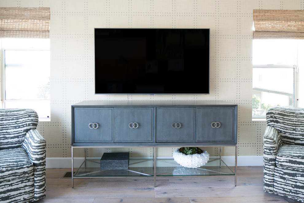 Ejemplo de salón para visitas abierto actual de tamaño medio con suelo de madera clara, televisor colgado en la pared y paredes grises