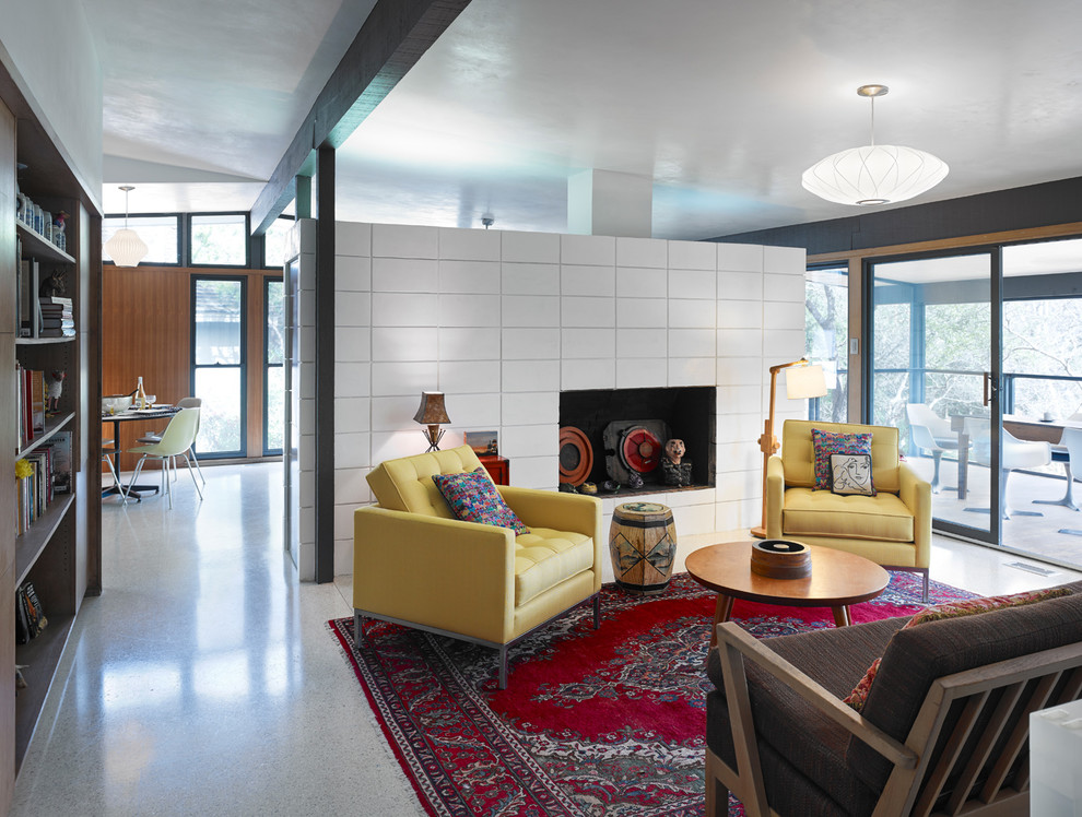 Стильный дизайн: гостиная комната в стиле ретро с с книжными шкафами и полками, белыми стенами и фасадом камина из плитки - последний тренд