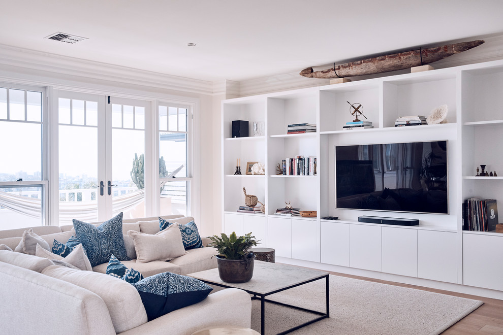 На фото: гостиная комната в морском стиле с бежевыми стенами, светлым паркетным полом, телевизором на стене и коричневым полом