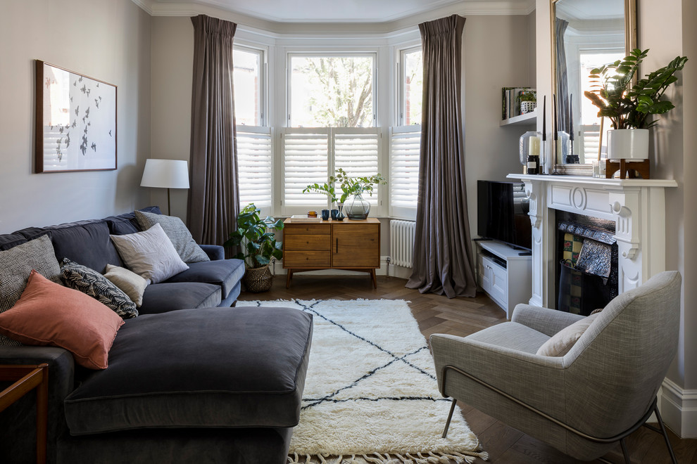 Inspiration pour un petit salon design avec un mur beige, un sol en bois brun, une cheminée standard, un téléviseur indépendant, un manteau de cheminée en bois et un sol marron.