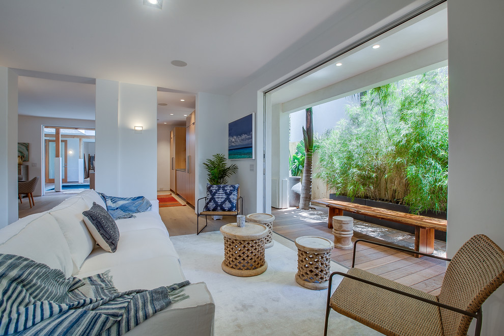 Foto de salón para visitas abierto tropical con paredes blancas, suelo de madera clara y suelo beige