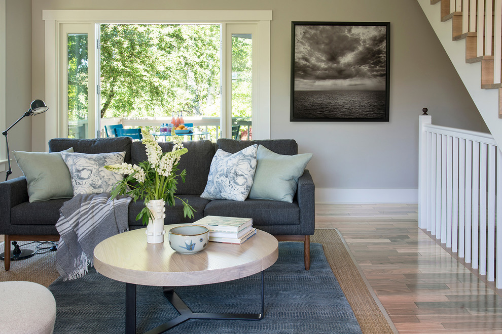 Kleines, Offenes Nordisches Wohnzimmer mit grauer Wandfarbe, hellem Holzboden, Kaminofen, Kaminumrandung aus Stein und beigem Boden in Seattle
