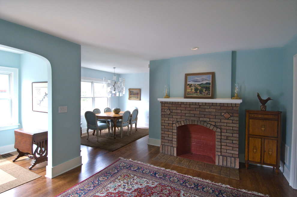 Imagen de salón abierto de estilo americano de tamaño medio con paredes azules, suelo de madera en tonos medios, todas las chimeneas y marco de chimenea de ladrillo
