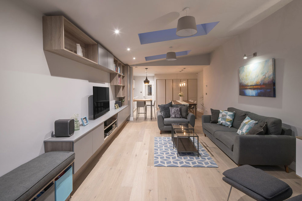 Mittelgroßes, Offenes Modernes Wohnzimmer mit weißer Wandfarbe, hellem Holzboden und Multimediawand in Dublin