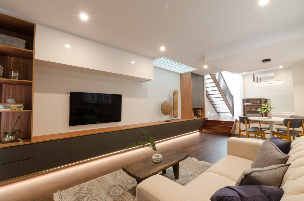 Esempio di un piccolo soggiorno minimalista aperto con pareti bianche, parquet scuro e parete attrezzata