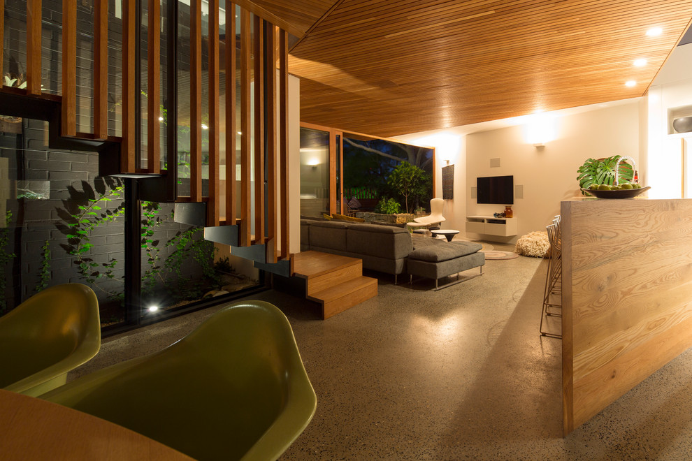 Свежая идея для дизайна: открытая гостиная комната среднего размера в современном стиле с белыми стенами, бетонным полом и телевизором на стене - отличное фото интерьера