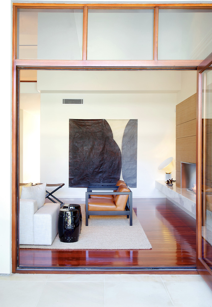 Mittelgroßes, Abgetrenntes Modernes Wohnzimmer mit weißer Wandfarbe, braunem Holzboden, Gaskamin, Kaminumrandung aus Holz und verstecktem TV in Brisbane