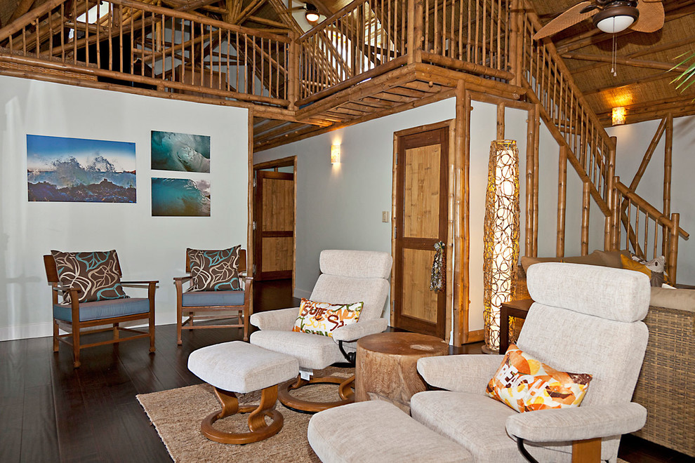 Diseño de salón abierto tropical con paredes blancas y suelo de madera oscura