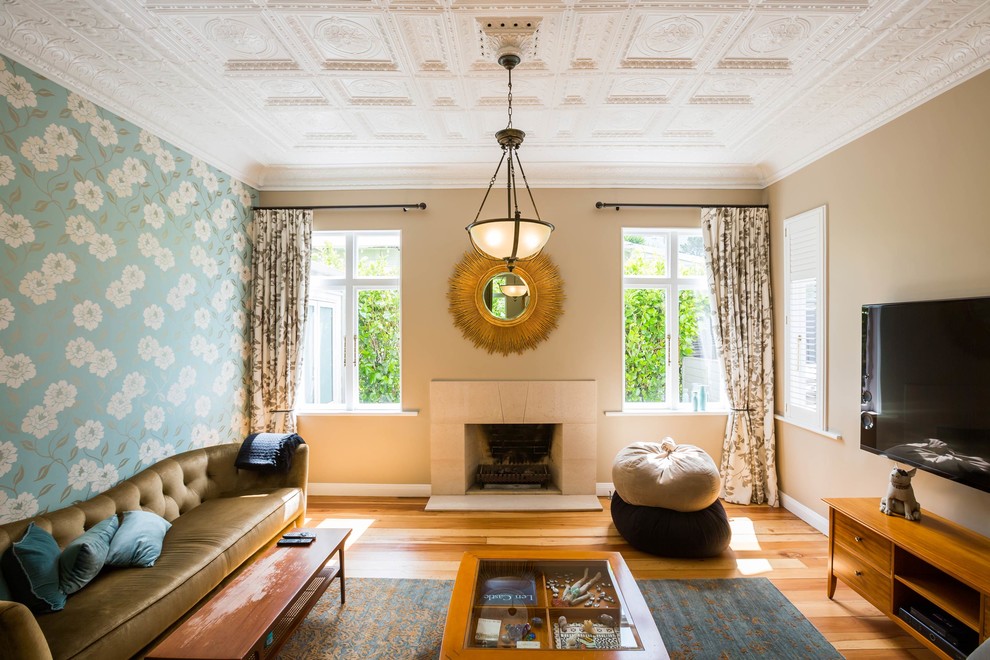 Modelo de salón clásico renovado con paredes beige, suelo de madera en tonos medios, todas las chimeneas, televisor colgado en la pared y suelo marrón