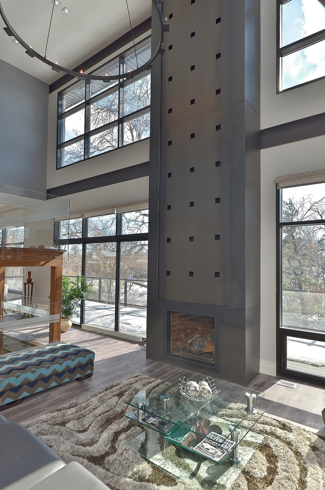 Modelo de salón para visitas tipo loft contemporáneo de tamaño medio con paredes grises, suelo de madera oscura, todas las chimeneas, marco de chimenea de metal y televisor colgado en la pared