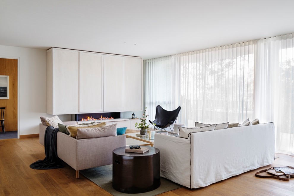 Immagine di un soggiorno minimal con pareti bianche, pavimento in legno massello medio, camino lineare Ribbon, TV nascosta e pavimento marrone