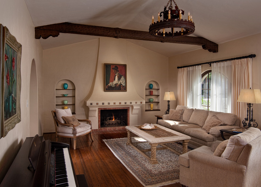 Exemple d'un salon méditerranéen avec un mur beige, un sol en bois brun, une cheminée standard et un manteau de cheminée en brique.