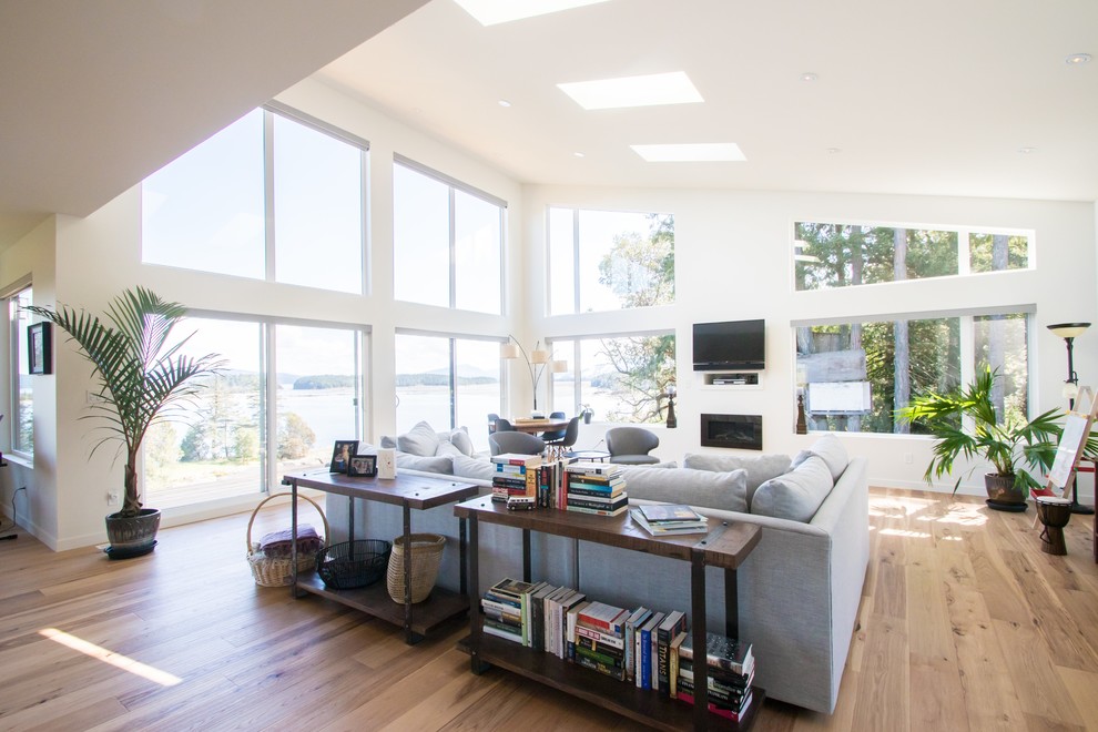Großes, Offenes Modernes Wohnzimmer mit weißer Wandfarbe, hellem Holzboden, Kamin, Kaminumrandung aus Metall, TV-Wand und braunem Boden in Vancouver