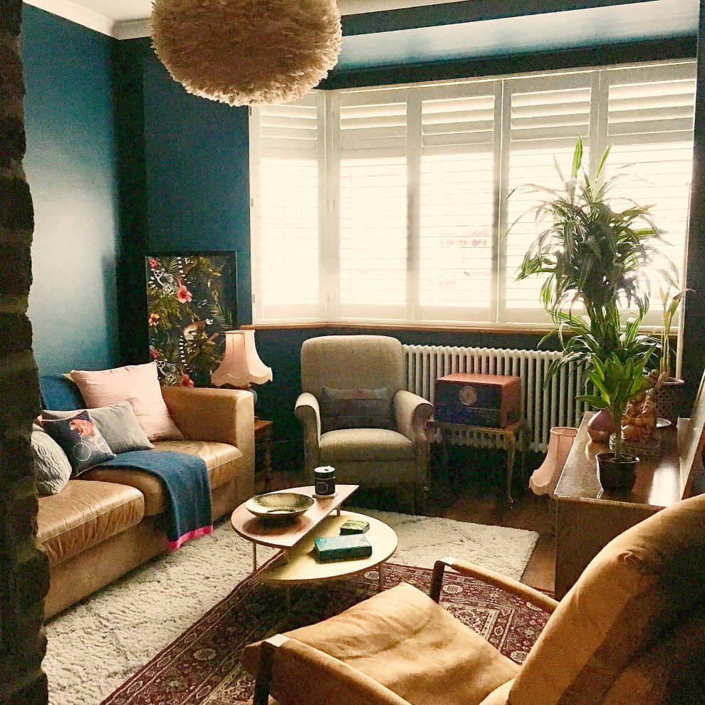 Foto på ett mellanstort 50 tals allrum med öppen planlösning, med blå väggar, en dubbelsidig öppen spis, en spiselkrans i tegelsten och brunt golv