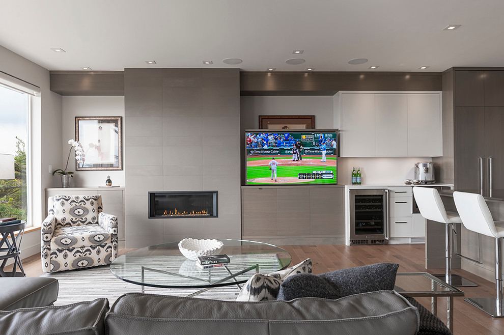 This is an example of a large contemporary open plan living room in Vancouver with white walls, medium hardwood flooring, a standard fireplace and a concealed tv.