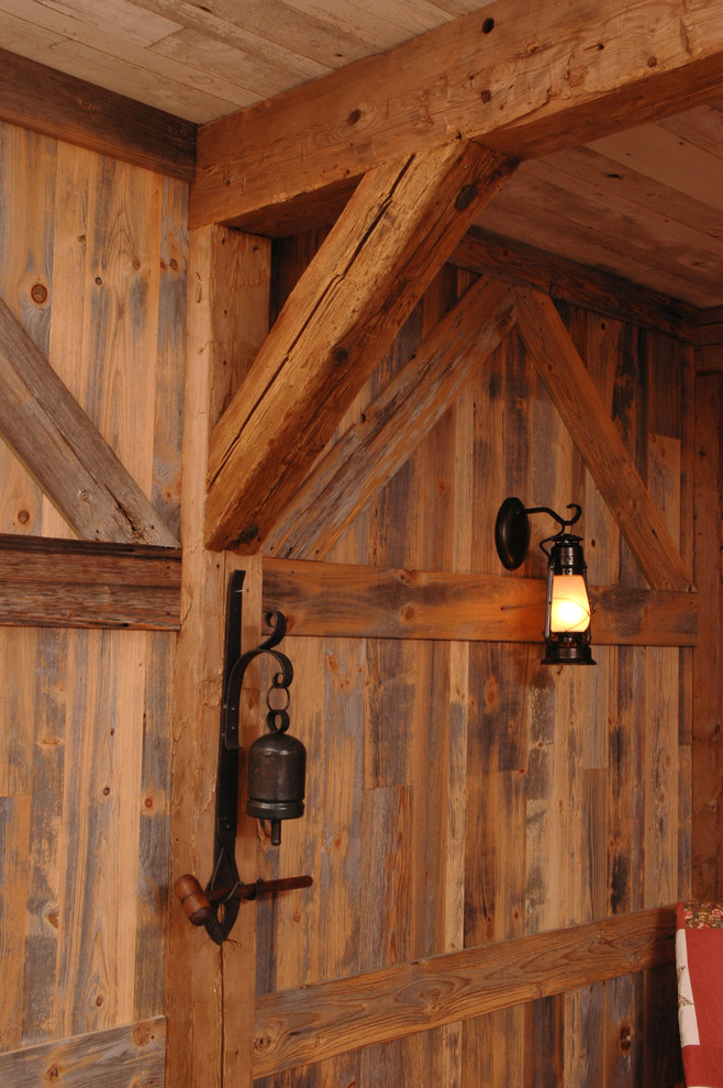 Foto de salón rural de tamaño medio con paredes rojas, suelo de madera en tonos medios, todas las chimeneas y marco de chimenea de piedra
