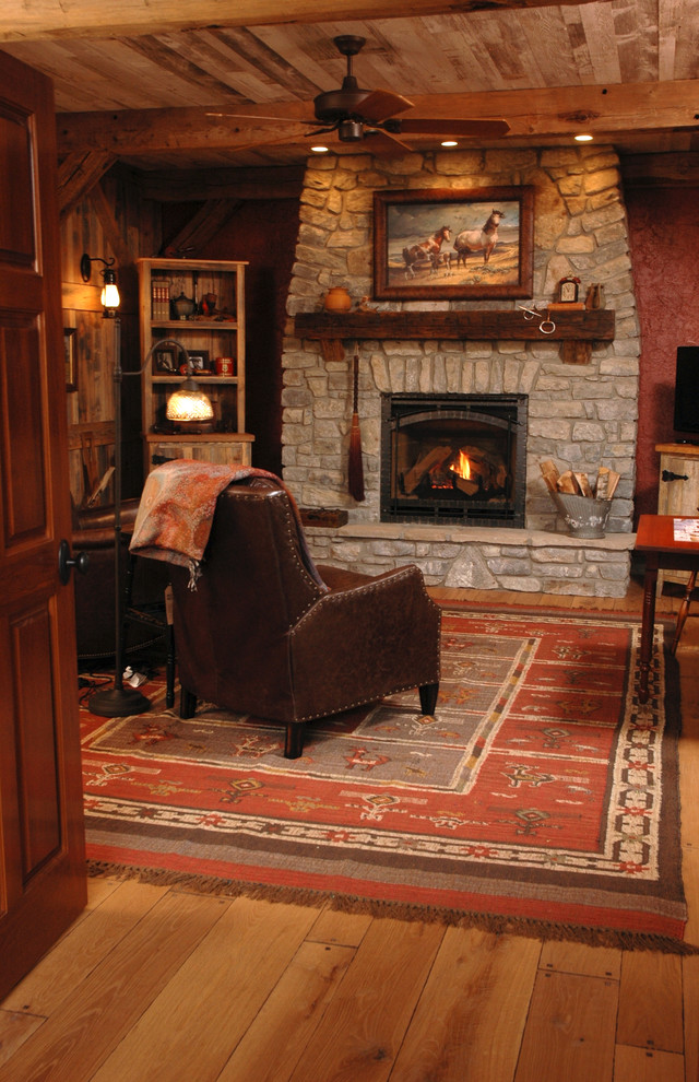 Imagen de salón rural de tamaño medio con paredes rojas, suelo de madera en tonos medios, todas las chimeneas y marco de chimenea de piedra