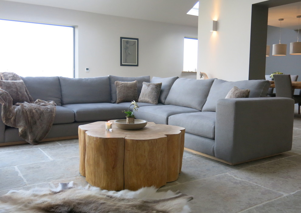 Cette image montre un grand salon design ouvert avec un mur gris, un sol en calcaire et un téléviseur encastré.