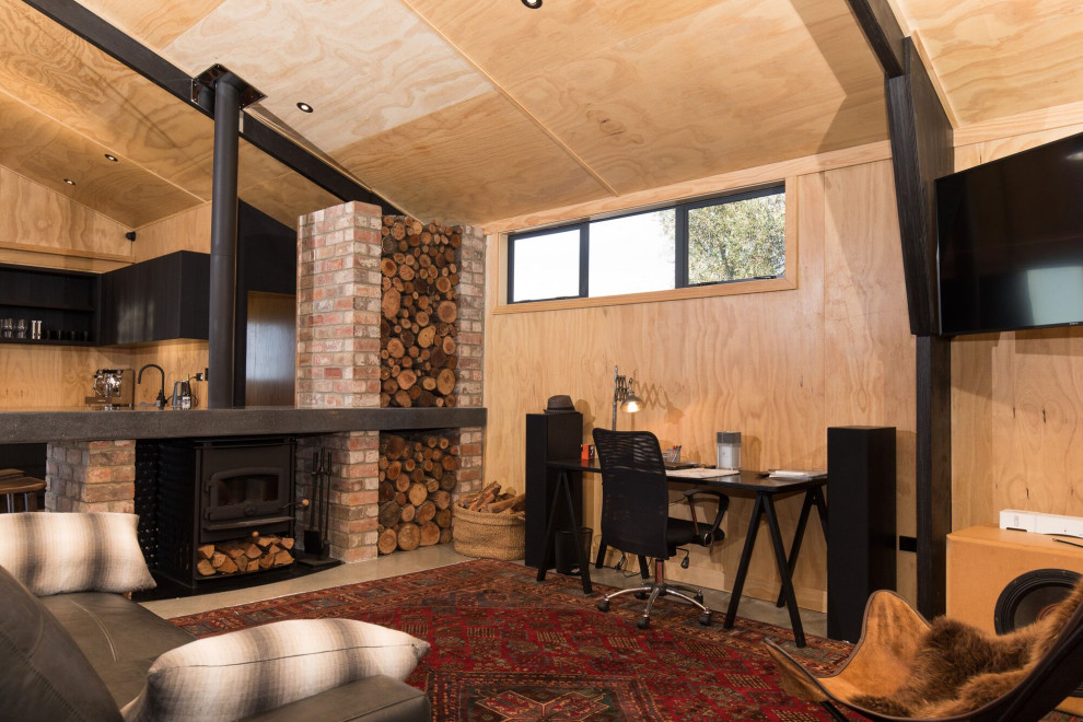 Стильный дизайн: открытая гостиная комната в стиле кантри с коричневыми стенами, печью-буржуйкой, телевизором на стене, серым полом, деревянным потолком и деревянными стенами - последний тренд