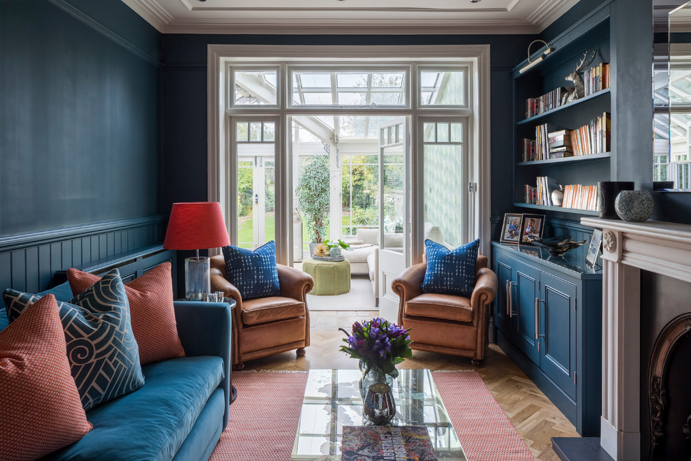 Idée de décoration pour un salon design ouvert avec une salle de réception, un mur bleu, parquet clair, une cheminée standard, un manteau de cheminée en pierre, un téléviseur encastré et un sol beige.