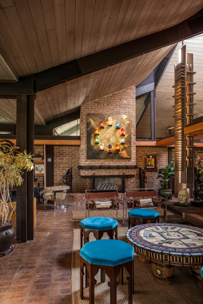Cette photo montre un grand salon tendance avec un manteau de cheminée en brique et tomettes au sol.