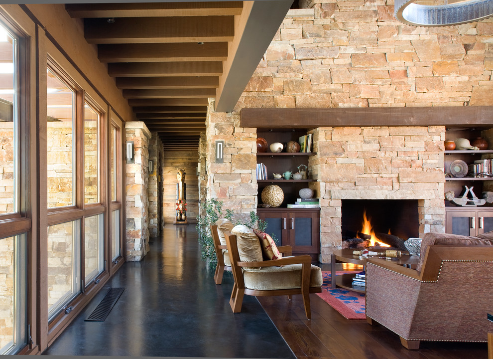 Exemple d'un salon chic ouvert avec sol en béton ciré, une cheminée standard et un manteau de cheminée en pierre.