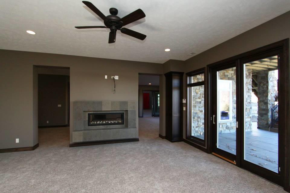 Large open plan living room in Other with brown walls, carpet, a two-sided fireplace and a tiled fireplace surround.