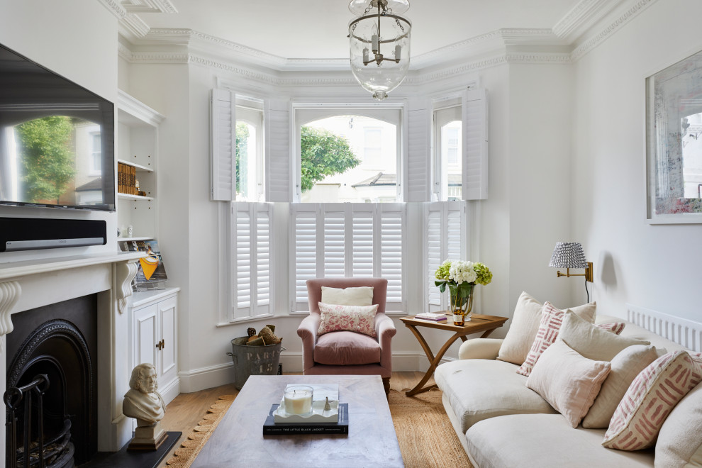 Abgetrenntes Klassisches Wohnzimmer mit weißer Wandfarbe, braunem Holzboden, Kamin, TV-Wand und braunem Boden in London