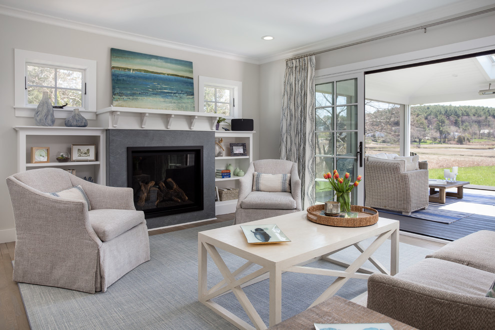 Inspiration for a coastal living room in Boston with grey walls, dark hardwood flooring, a standard fireplace, a stone fireplace surround and brown floors.