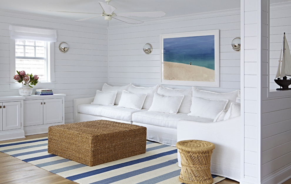 На фото: маленькая открытая гостиная комната в морском стиле с белыми стенами, светлым паркетным полом и телевизором на стене без камина для на участке и в саду с
