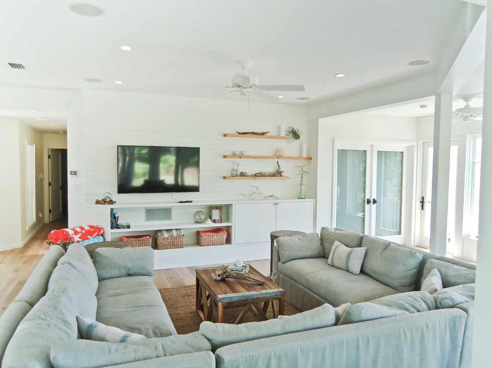 Small coastal open plan living room in Miami with white walls, light hardwood flooring, no fireplace, a wall mounted tv and feature lighting.