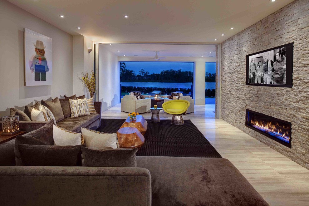 На фото: огромная гостиная комната в современном стиле с горизонтальным камином, фасадом камина из камня, телевизором на стене и коричневым диваном с