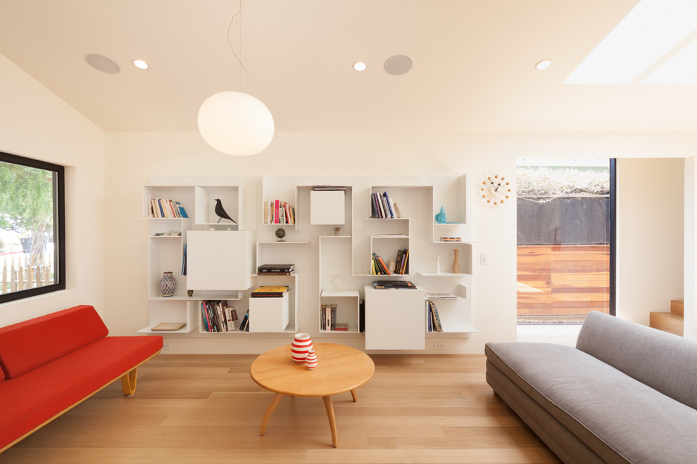 Inspiration for a small scandinavian open concept medium tone wood floor living room library remodel in Los Angeles with white walls, no tv and no fireplace
