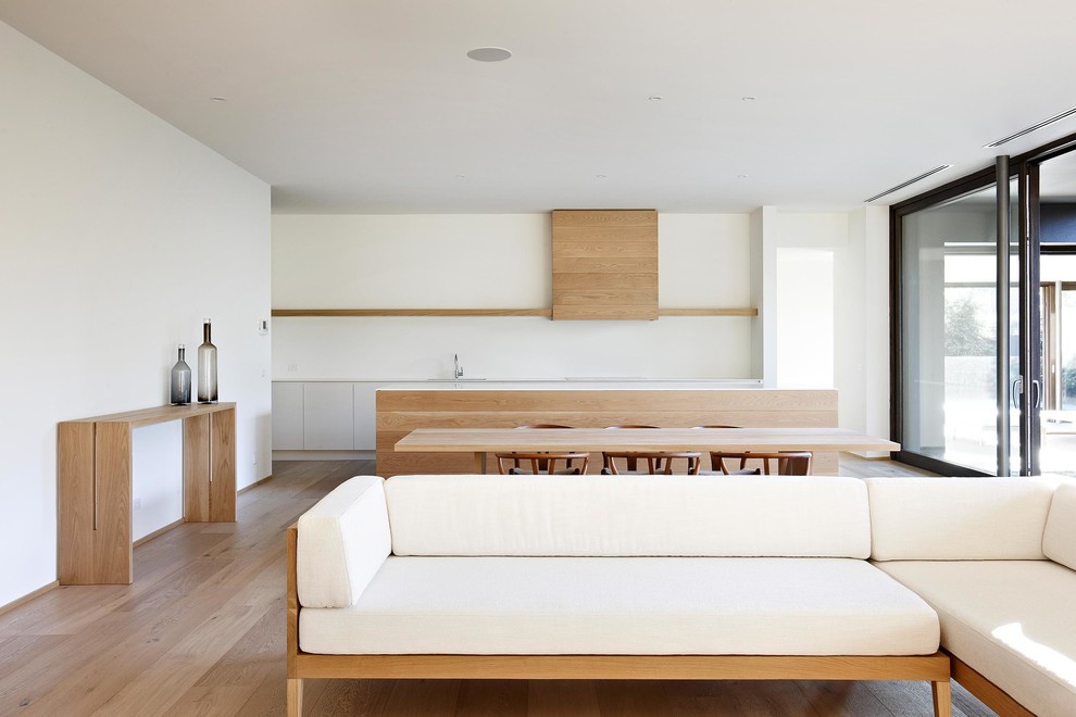Идея дизайна: открытая гостиная комната в скандинавском стиле с белыми стенами и светлым паркетным полом