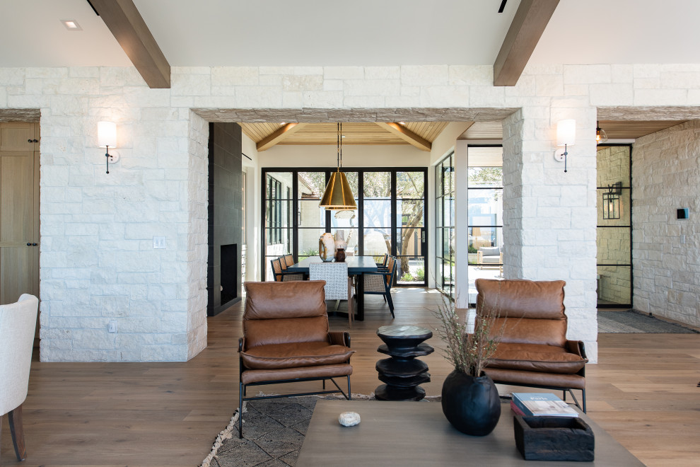 Example of a mid-sized transitional open concept light wood floor and brown floor living room design in Orange County with white walls, a standard fireplace, a stone fireplace and no tv
