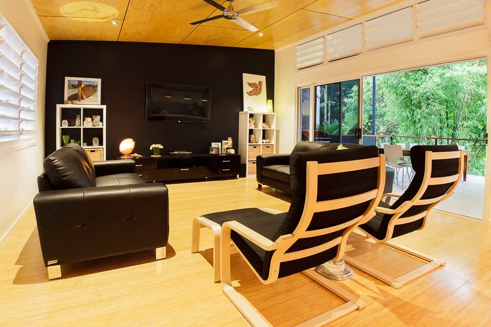 Источник вдохновения для домашнего уюта: открытая гостиная комната среднего размера в стиле модернизм с черными стенами, полом из бамбука и телевизором на стене